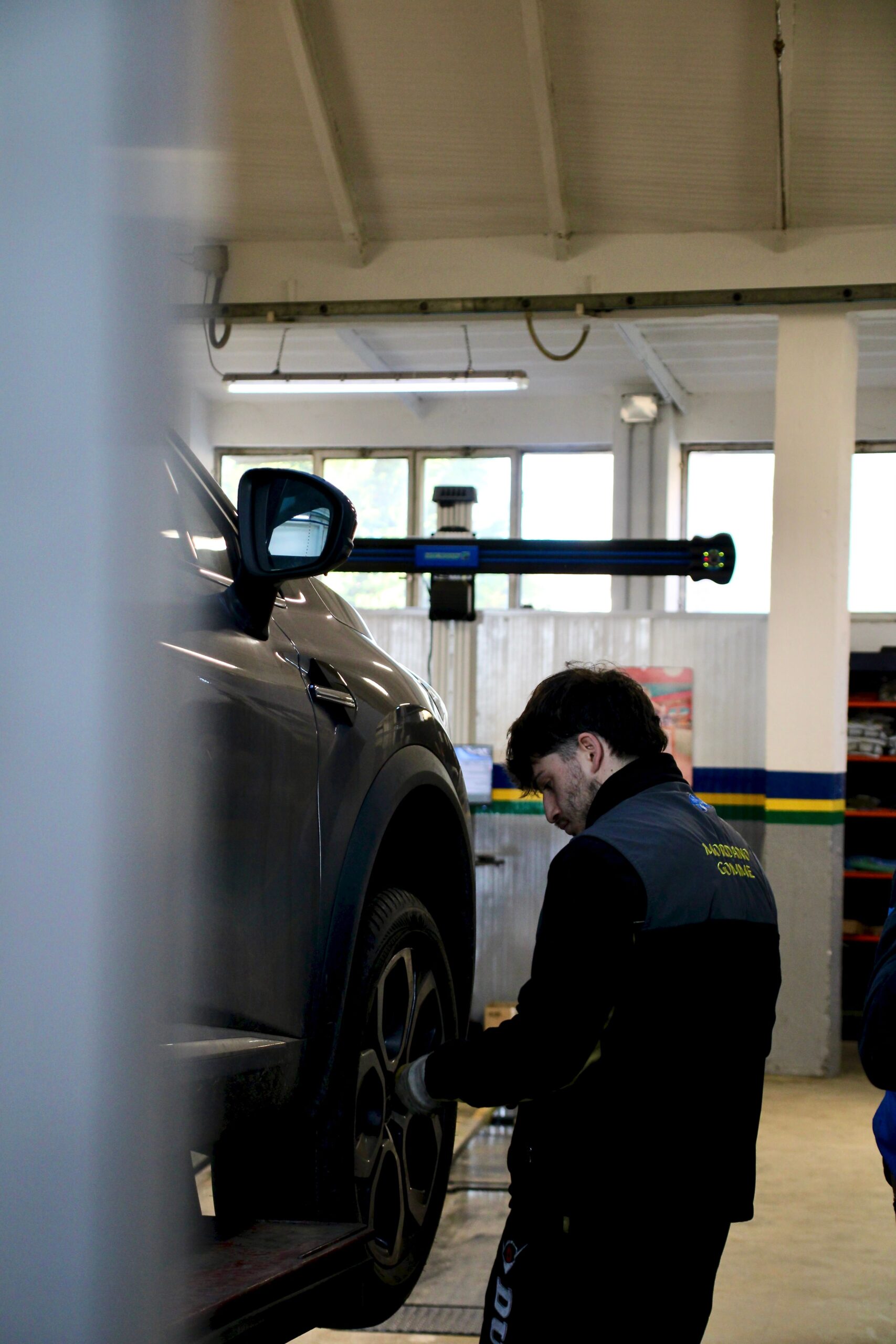 Mechanic adjusting car tire on lift in an indoor workshop setting.