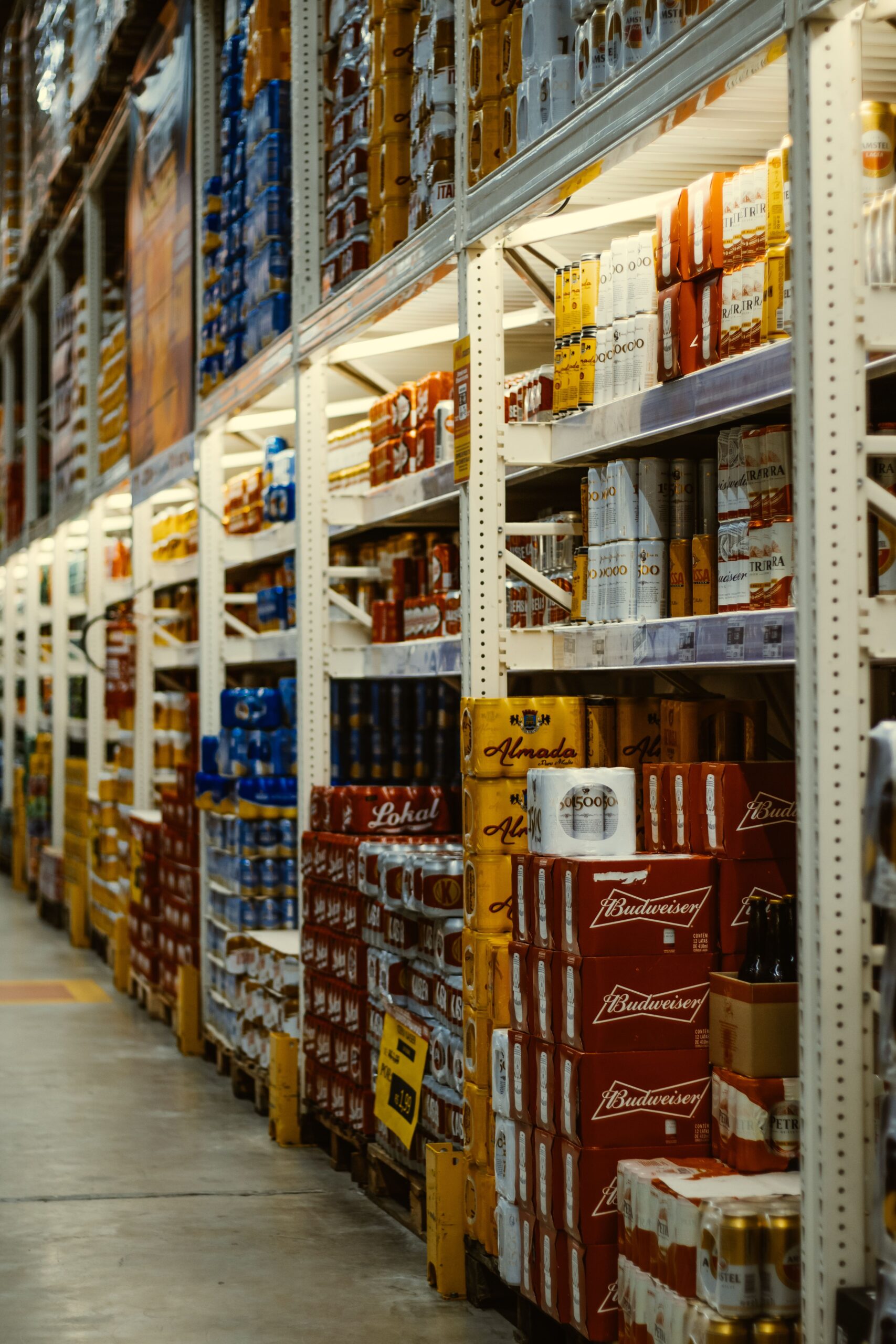 Rows of beer and beverages stacked neatly in a supermarket aisle.